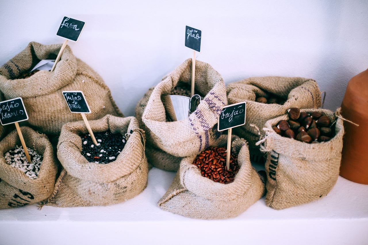 From above of organic bags with assorted beans and chestnuts with signboards on shelf for sale