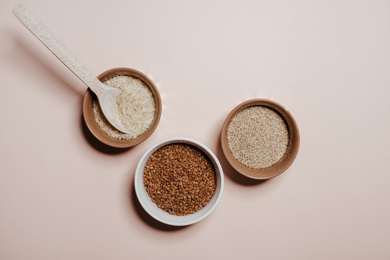 Flat lay of bowls containing seeds and grains on a neutral background, emphasizing natural textures.